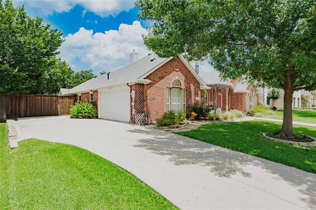 2314 Ranch Road Sachse, TX 75048 - Photo 2 of 27 Brick exterior with white trim, a concrete driveway, an attached garage, a manicured lawn, and mature trees