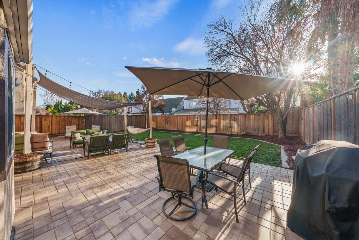 7385 Forsum Road San Jose, CA 95138 - Photo 32 of 40 a view of a patio with table and chairs under an umbrella with a barbeque grill and wooden fence