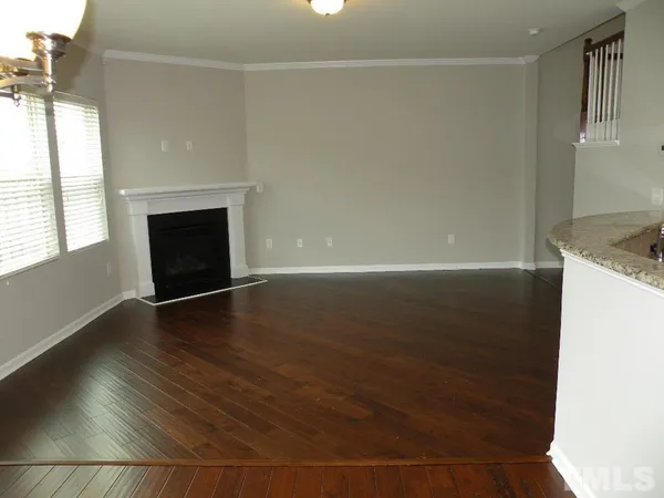 an empty room with wooden floor fireplace and windows