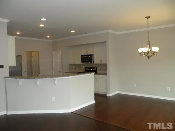 a view of an empty room with kitchen view and a window