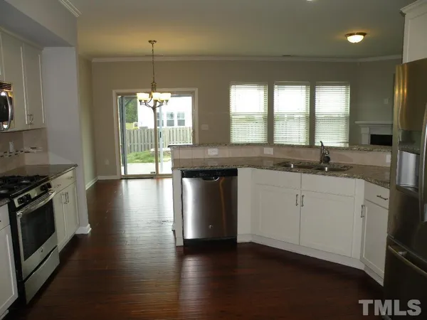 a kitchen with stainless steel appliances granite countertop a sink a stove and a wooden floors