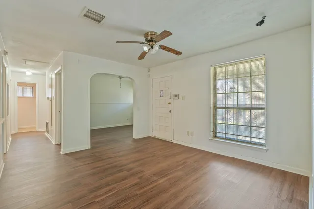 an empty room with wooden floor cabinet and windows