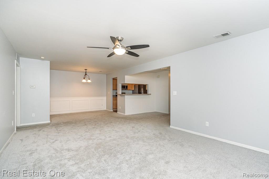 3491 Tremonte Circle Rochester, MI 48306 - Photo 10 of 42 Expansive carpeted living space featuring a ceiling fan with integrated lighting, recessed lighting, and a dining area with a chandelier
