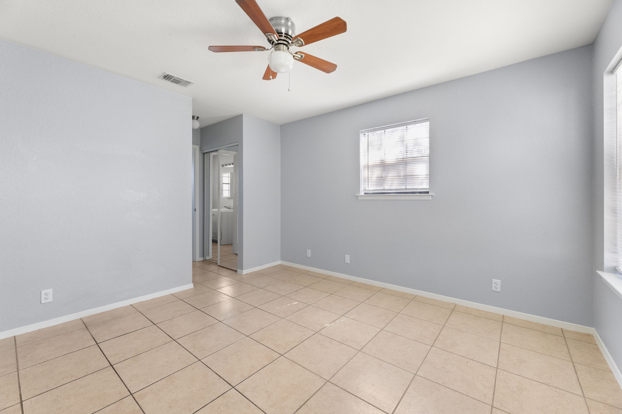 3802 Foust Trail, Unit A Georgetown, TX 78628 - Photo 17 of 34 A well-lit bedroom features cool tile flooring, a ceiling fan, and ample natural light from a window.