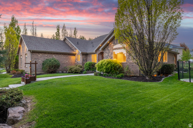 6208 West Bull River Road Highland, UT 84003 - Photo 76 of 90 Brick and stone exterior with arched windows, mature landscaping, and a manicured lawn