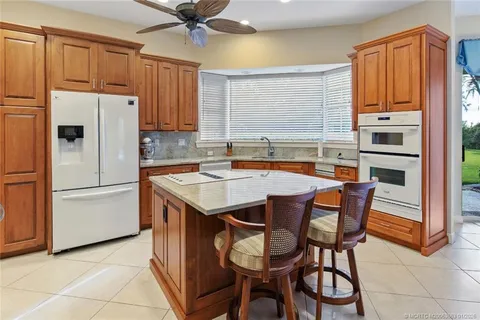 a kitchen with stainless steel appliances a white table chairs and a refrigerator