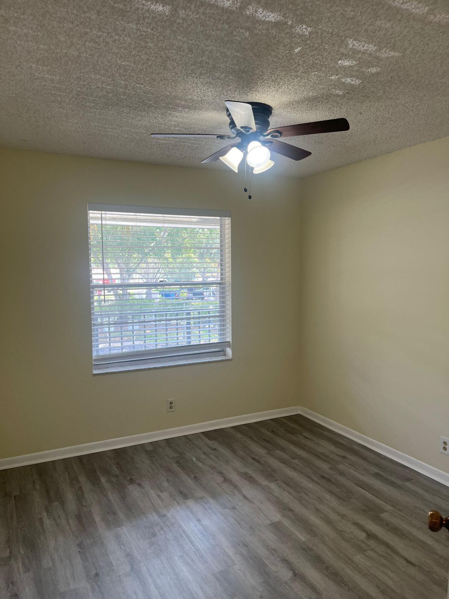9993 Three Lakes Circle Boca Raton, FL 33428 - Photo 10 of 22 an empty room with wooden floor chandelier fan and windows
