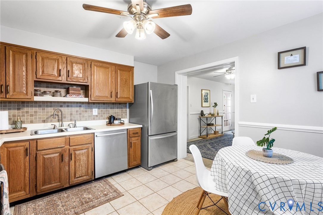 6020 Bonneau Road Richmond, VA 23227 - Photo 14 of 36 a kitchen with stainless steel appliances granite countertop a refrigerator a sink dishwasher a stove a dining table and chairs with wooden floor