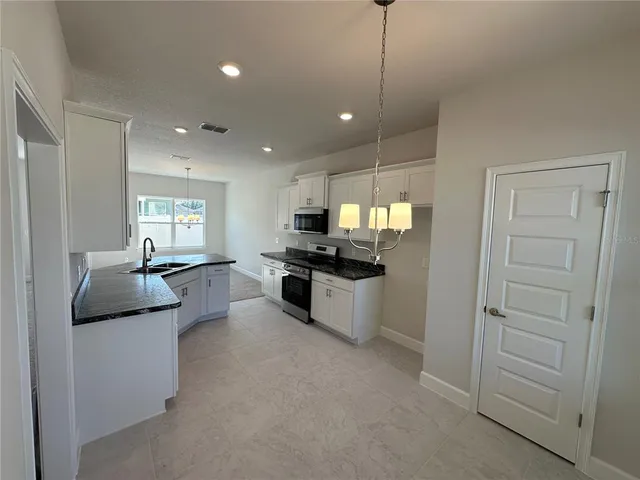 a kitchen with kitchen island white cabinets and stainless steel appliances
