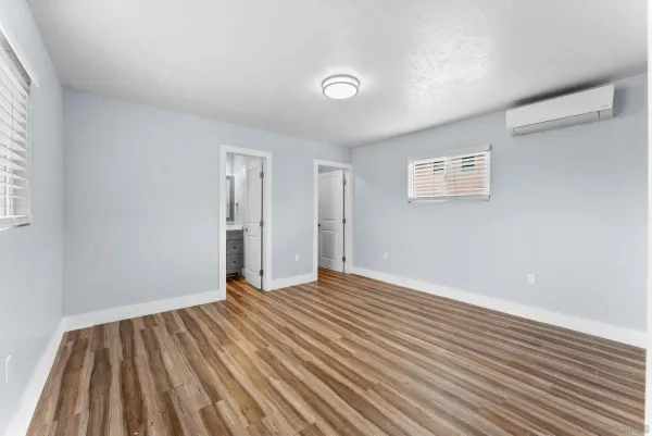 a view of an empty room with wooden floor and a window