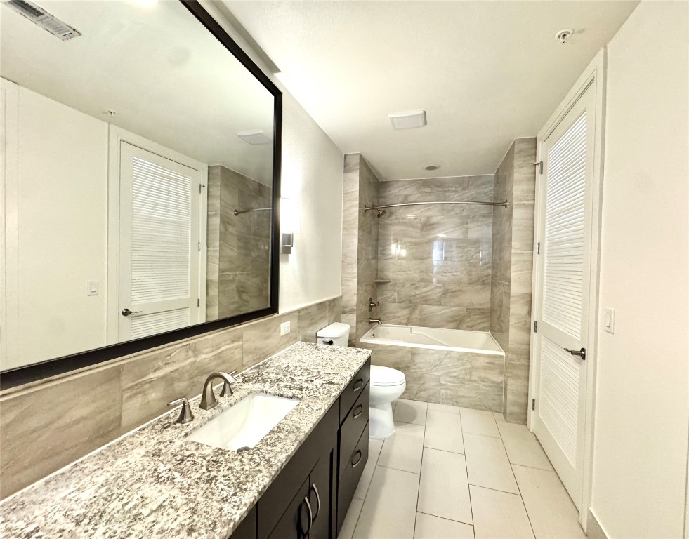 2303 Mid Lane, Unit 710 Houston, TX 77027 - Photo 14 of 19 a bathroom with a granite countertop sink mirror bathtub and shower