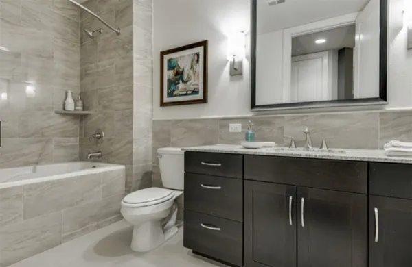 a bathroom with a double vanity sink a toilet and shower