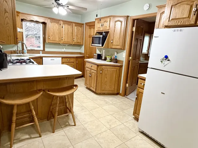 a kitchen with granite countertop a refrigerator a stove a sink dishwasher and white cabinets with wooden floor