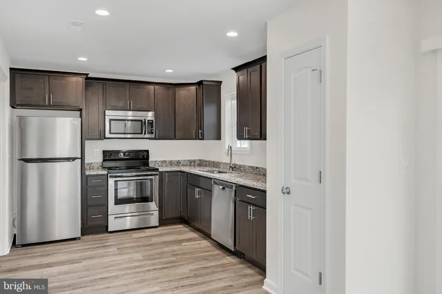 a kitchen with kitchen island granite countertop stainless steel appliances and wooden cabinets