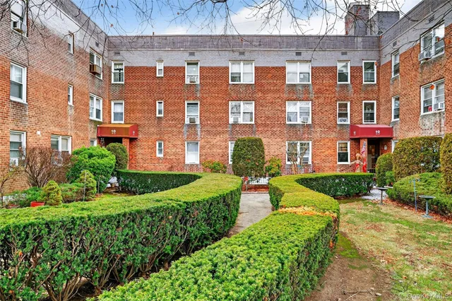 a front view of a building with garden and trees