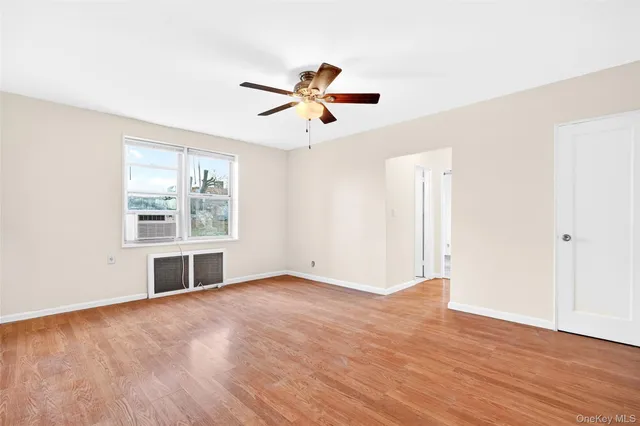 an empty room with wooden floor chandelier fan and windows