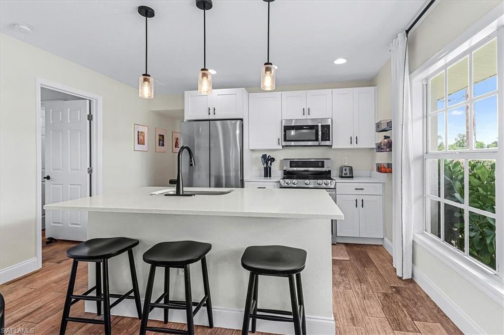 18601 Geranium Road Fort Myers, FL 33967 - Photo 5 of 34 a kitchen with stainless steel appliances a stove a refrigerator and white cabinets next to a window