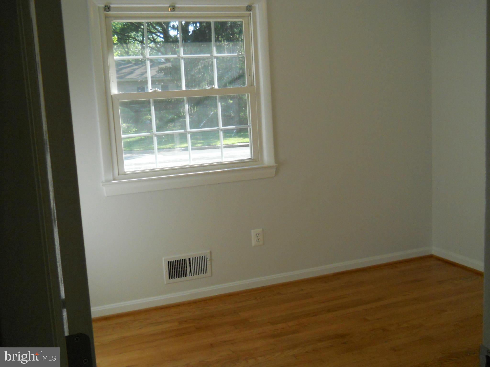 13145 Clifton Road Silver Spring, MD 20904 - Photo 18 of 30 an empty room with wooden floor and windows