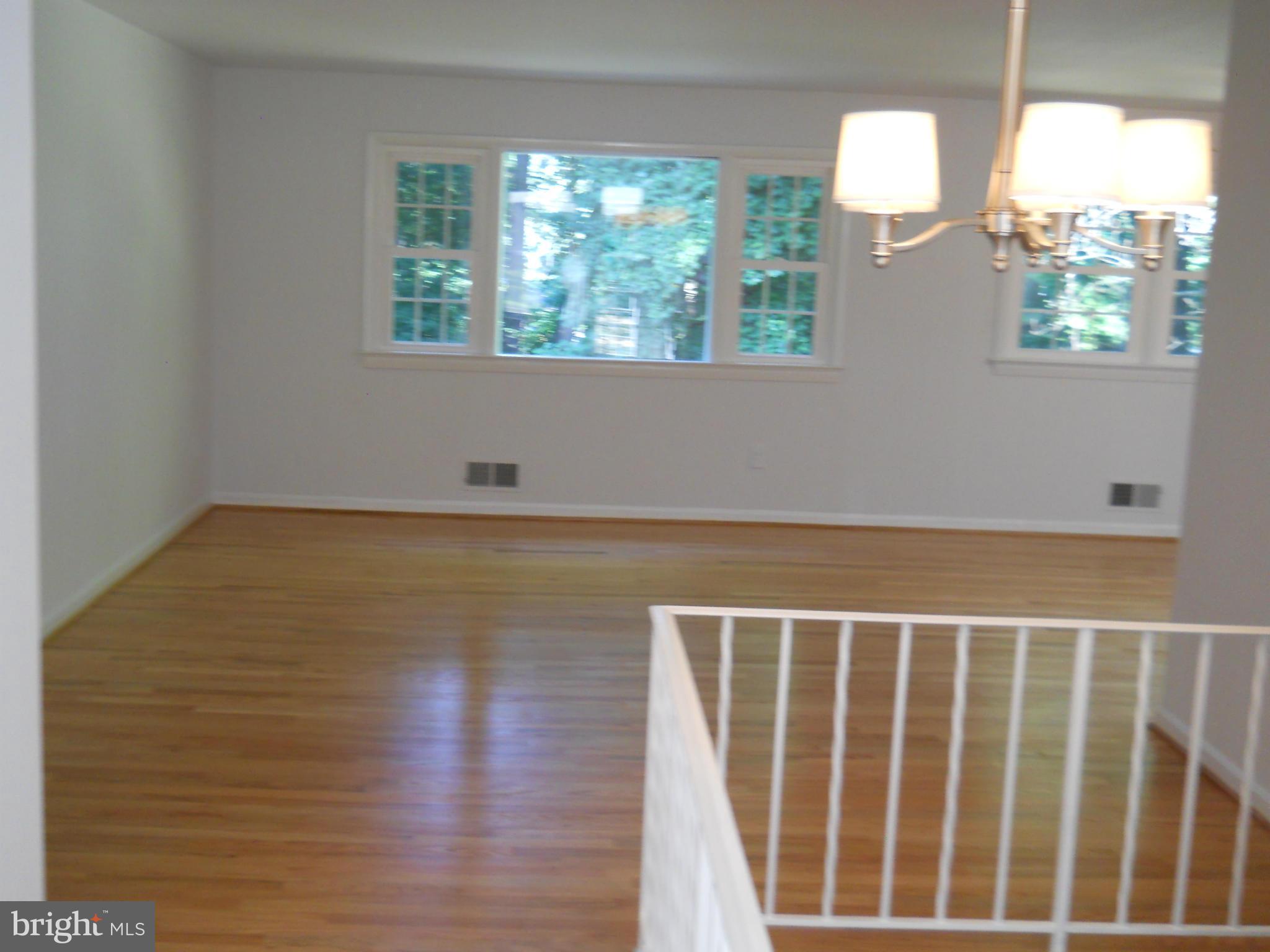 13145 Clifton Road Silver Spring, MD 20904 - Photo 5 of 30 a view of an empty room with wooden floor and a window