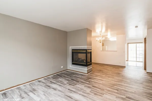 an empty room with wooden floor fireplace and windows