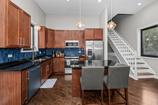 a kitchen with stainless steel appliances kitchen island granite countertop a stove a sink a microwave and a refrigerator