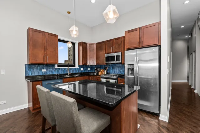 a kitchen with stainless steel appliances granite countertop a sink a stove and a refrigerator
