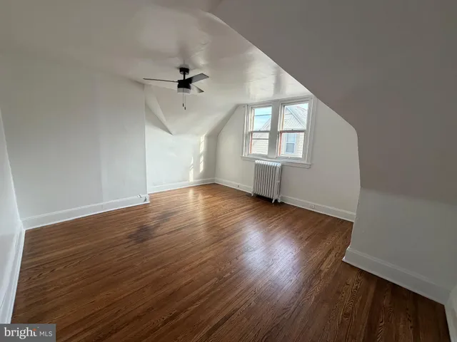 an empty room with wooden floor ceiling fan and windows