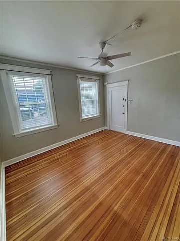 a view of an empty room with wooden floor and a window