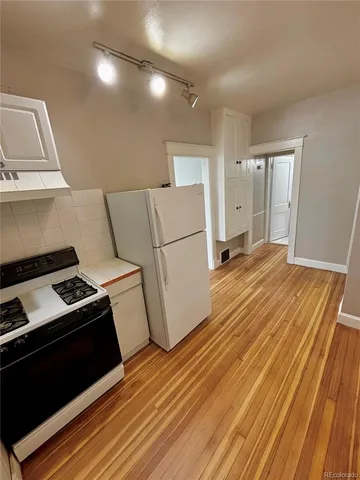 a kitchen with a refrigerator stove and wooden floor