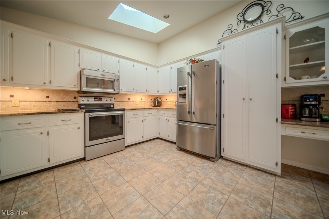 1394 Saxe Road Mogadore, OH 44260 - Photo 13 of 39 Kitchen with tasteful backsplash, a skylight, stainless steel appliances, and white cabinets