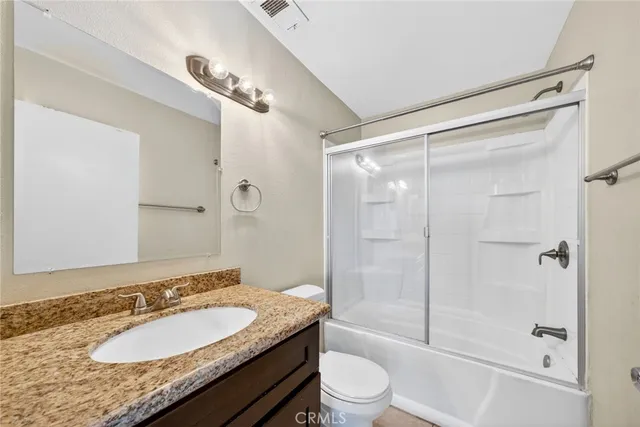 a bathroom with a granite countertop sink toilet mirror and shower