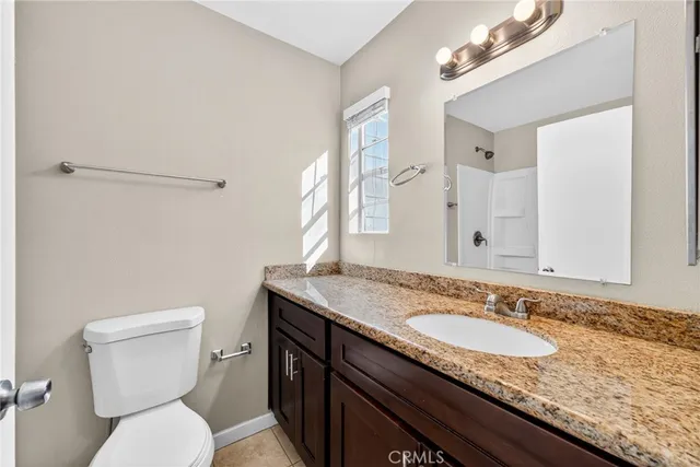 a bathroom with a granite countertop sink a toilet and a mirror