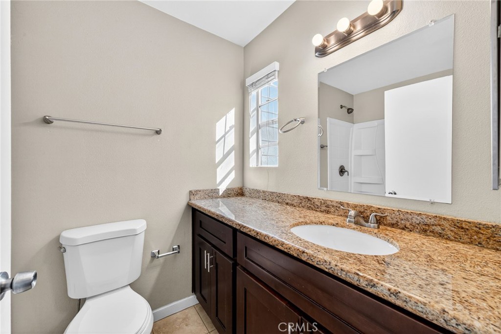 14380 Foothill Boulevard Sylmar, CA 91342 - Photo 22 of 27 a bathroom with a granite countertop sink a toilet and a mirror