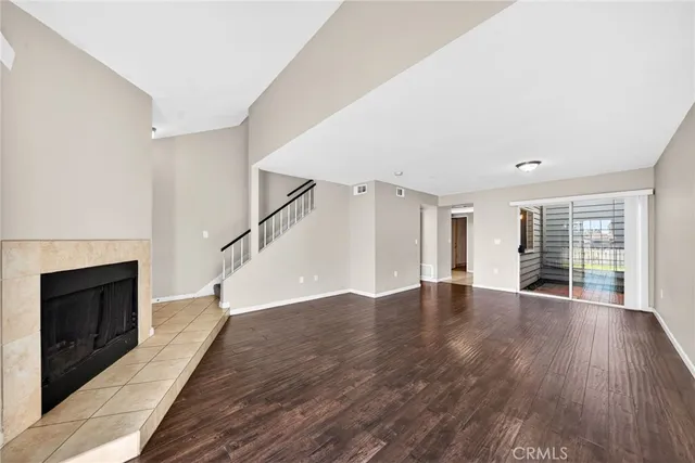 a view of an empty room with wooden floor fireplace and a window