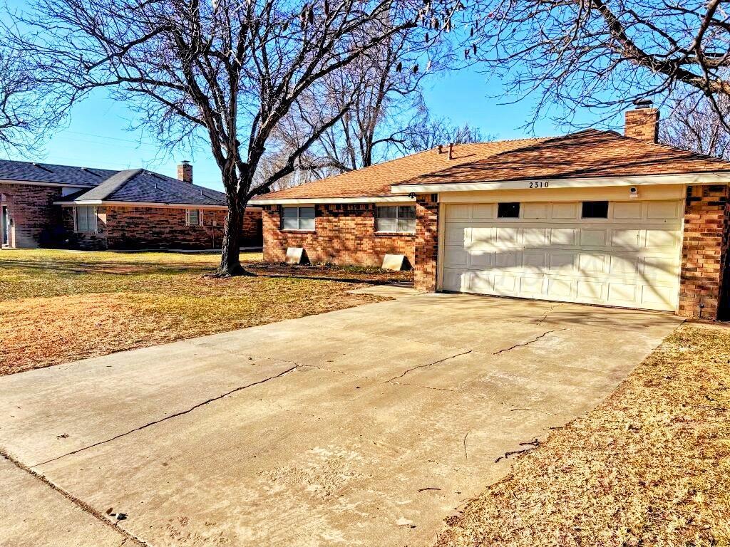 2310 Texas Street Perryton, TX 79070 - Photo 1 of 26 a view of a white house with a large tree with yard