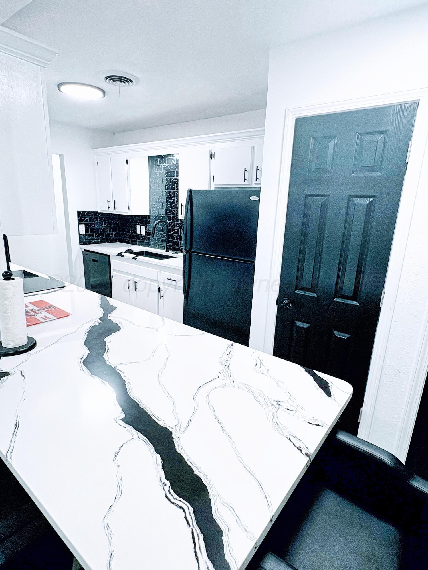 2310 Texas Street Perryton, TX 79070 - Photo 9 of 26 a kitchen with a refrigerator and wooden cabinets