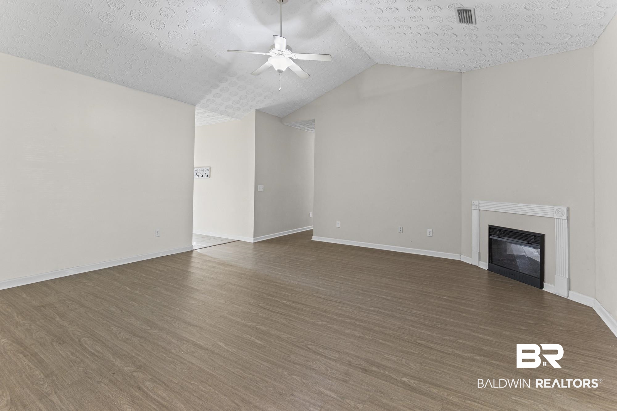 1153 Sloane Cove Foley, AL 36535 - Photo 5 of 25 Unfurnished living room with a ceiling fan, a glass covered fireplace, and dark wood-type flooring