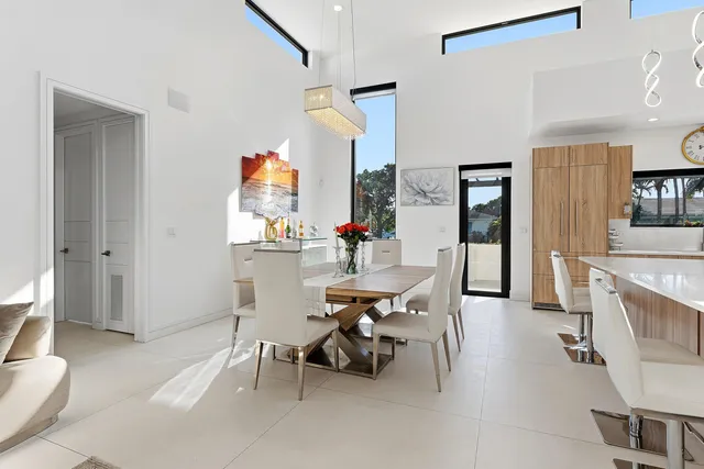 a living room with stainless steel appliances kitchen island granite countertop a dining table chairs and a sink