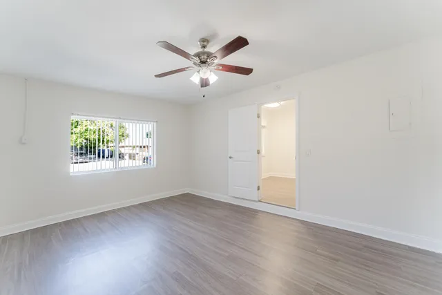 a view of an empty room with wooden floor and a window