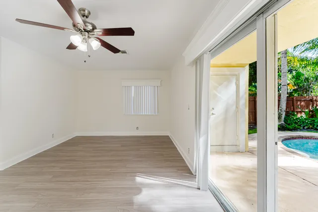 an empty room with wooden floor fan and windows