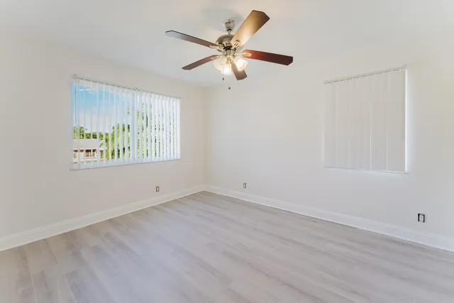 an empty room with window and ceiling fan