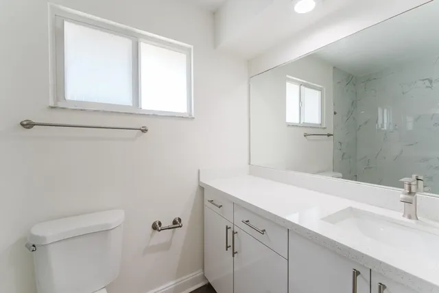 a bathroom with a sink a toilet and a window