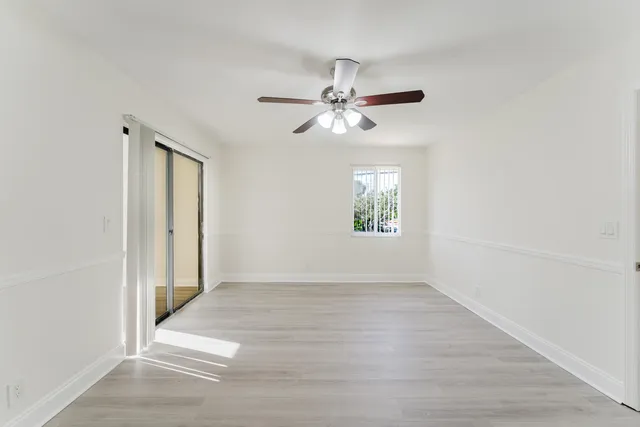 an empty room with windows and fan