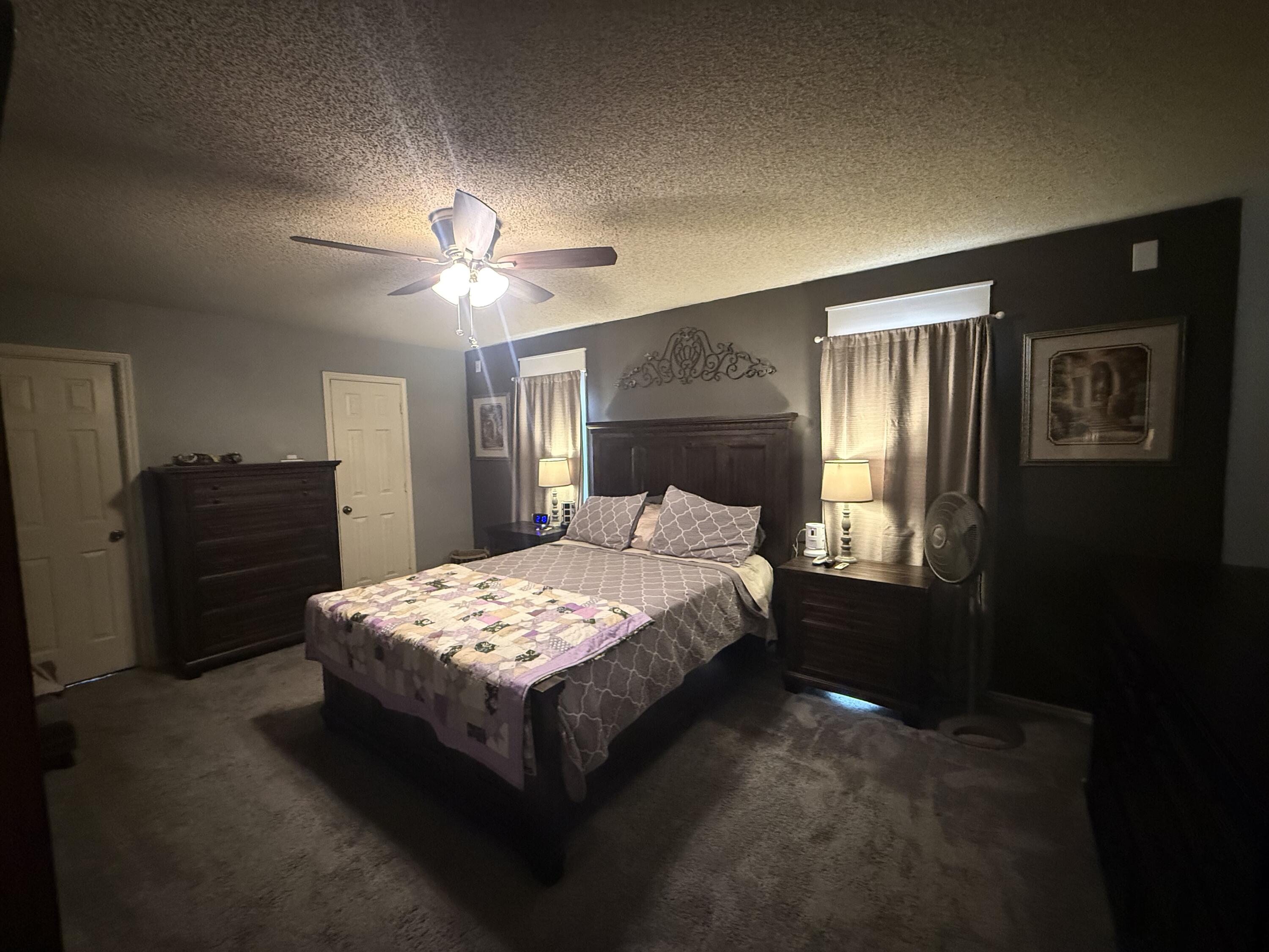 6906 8th Street Lubbock, TX 79416 - Photo 18 of 42 a bedroom with a bed and a chandelier