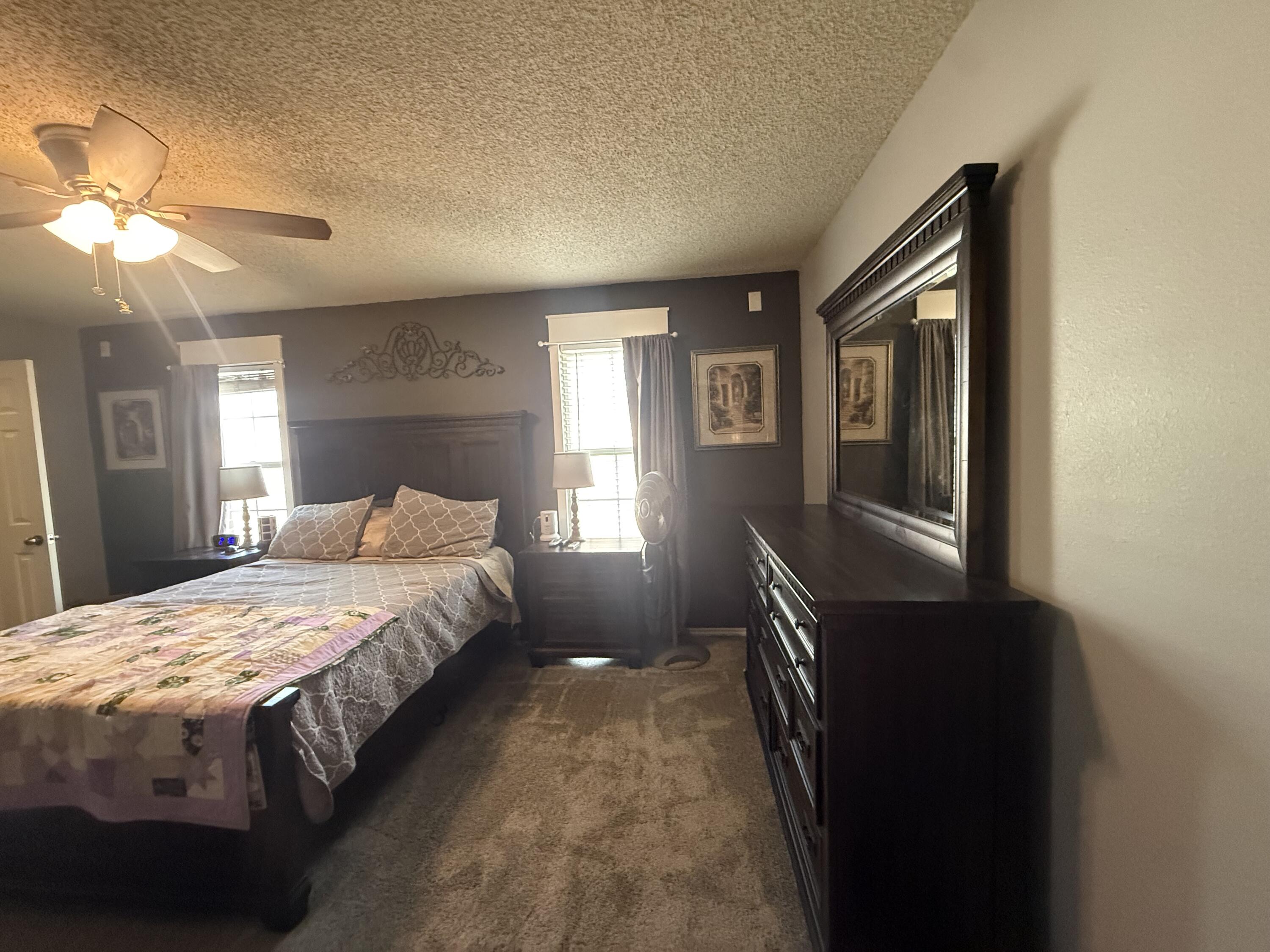 6906 8th Street Lubbock, TX 79416 - Photo 19 of 42 a bedroom with a bed and a chandelier
