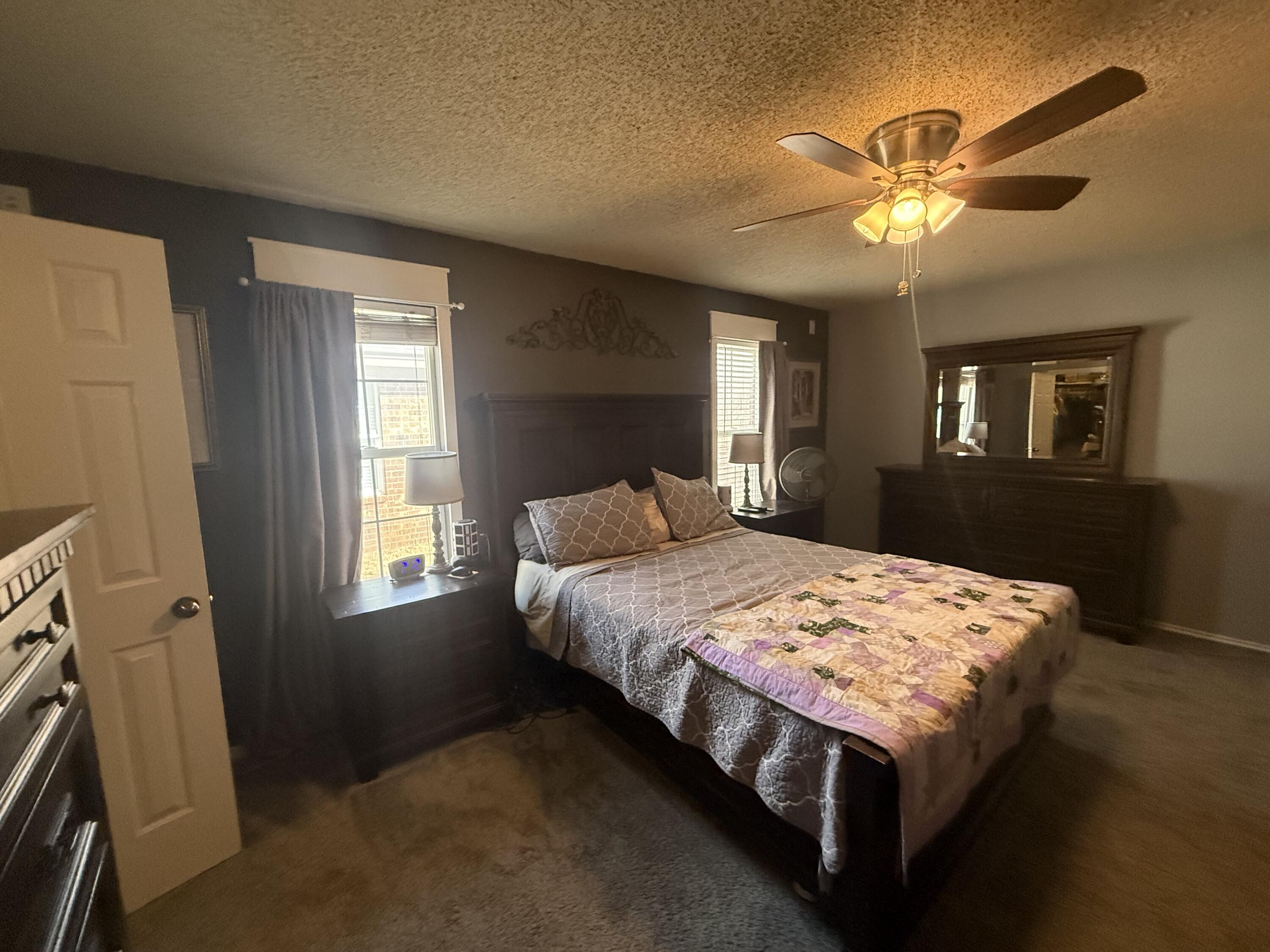 6906 8th Street Lubbock, TX 79416 - Photo 20 of 42 a bedroom with a bed and a chandelier
