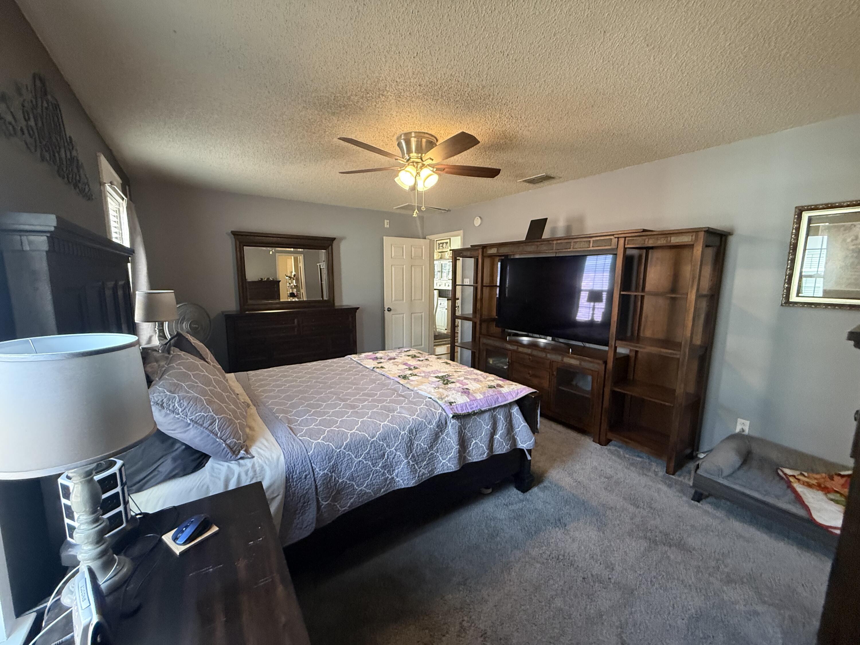 6906 8th Street Lubbock, TX 79416 - Photo 21 of 42 a bedroom with a bed and a flat tv screen on wall
