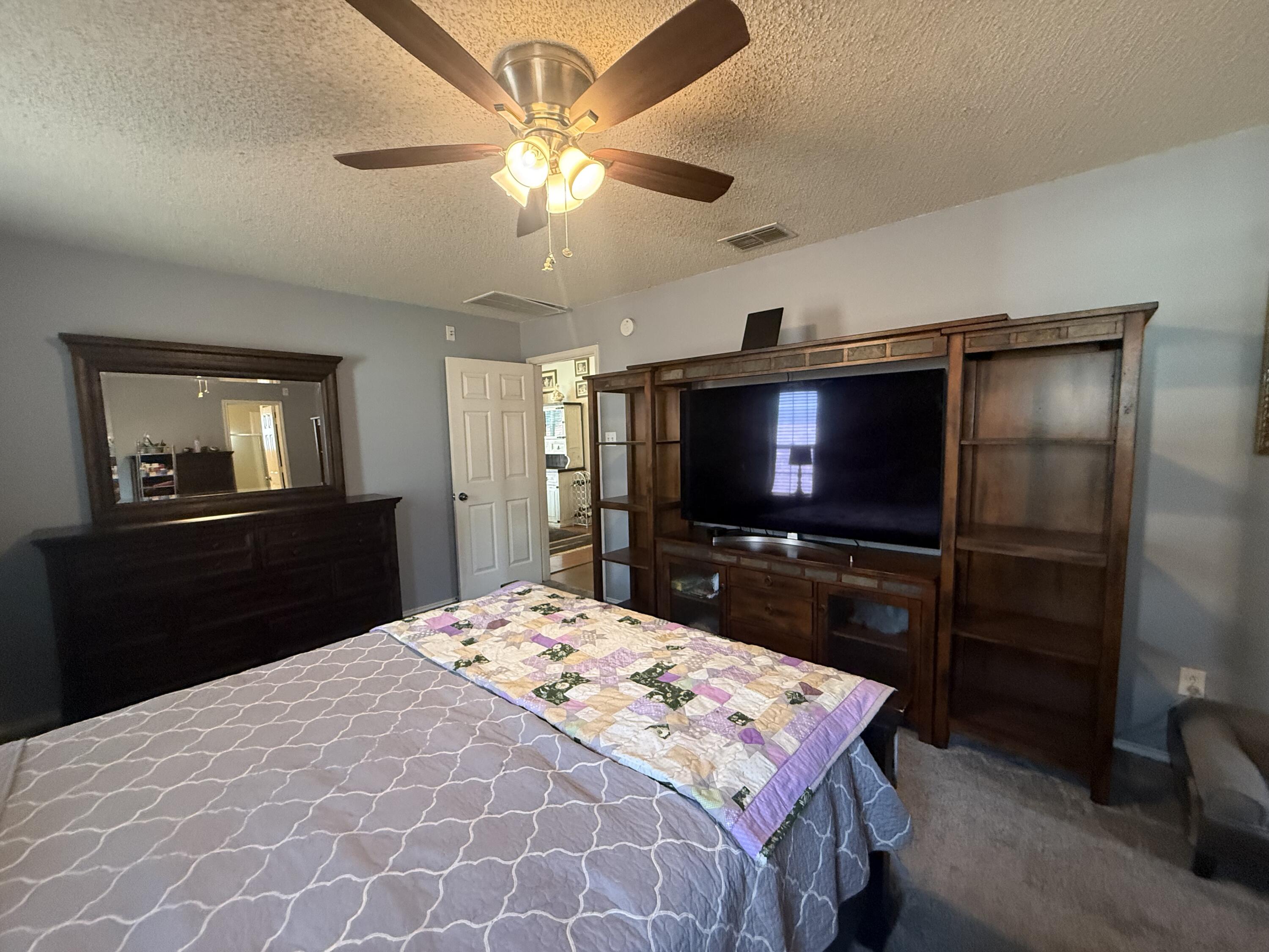 6906 8th Street Lubbock, TX 79416 - Photo 22 of 42 a bedroom with a bed and a flat screen tv
