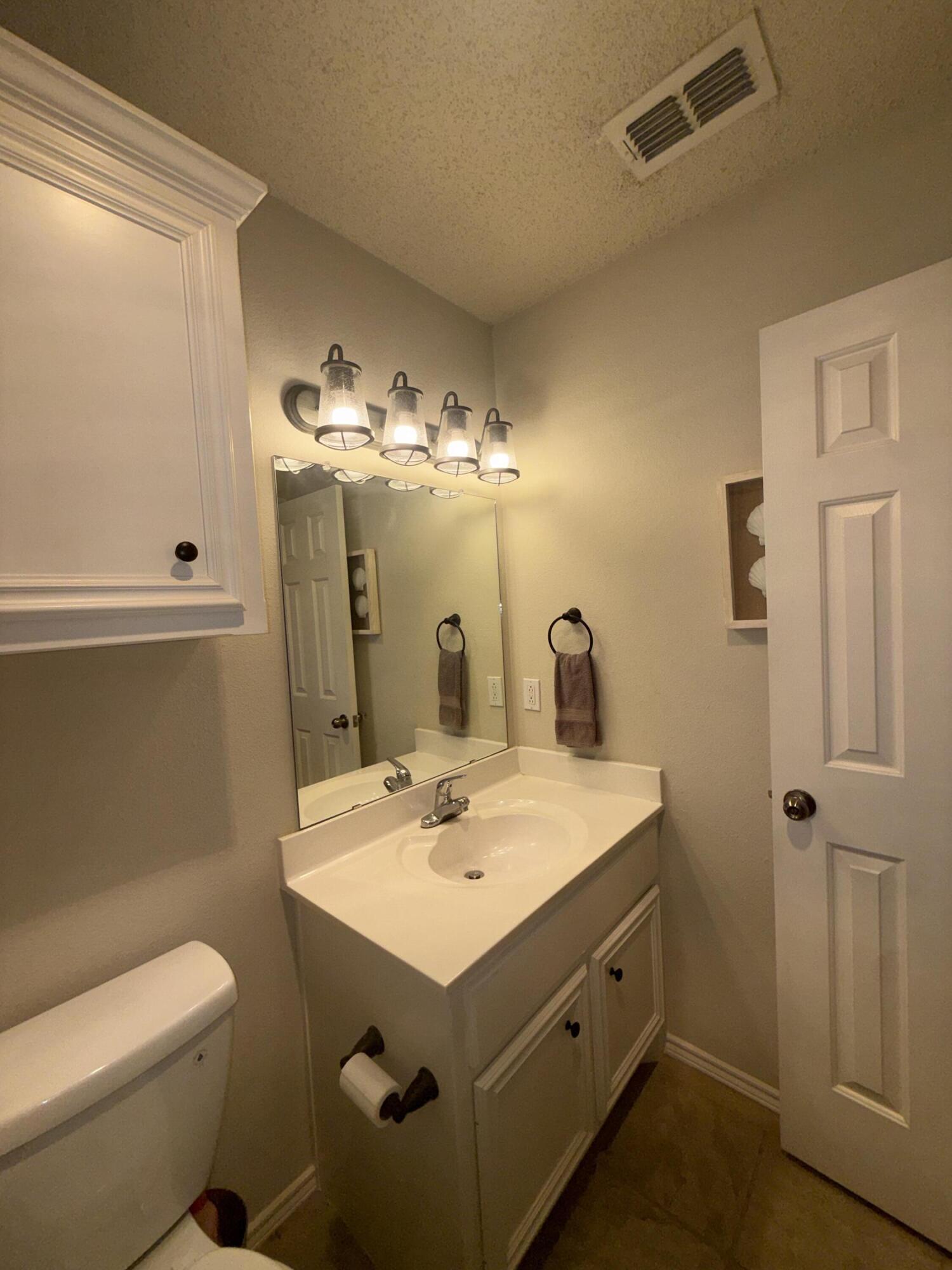 6906 8th Street Lubbock, TX 79416 - Photo 30 of 42 a bathroom with a sink toilet and mirror