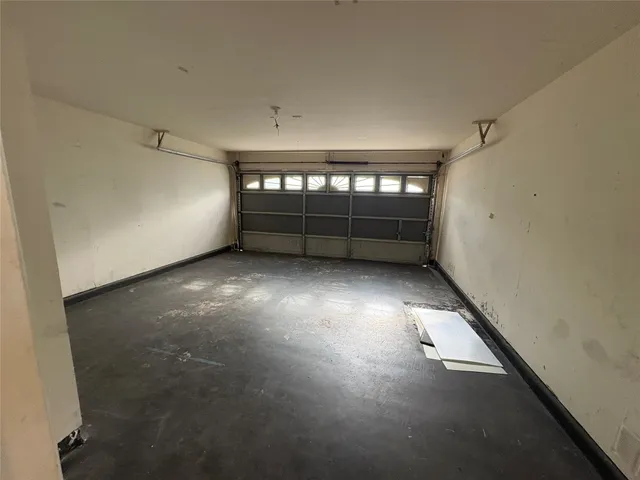 an empty room with a window and chandelier fan
